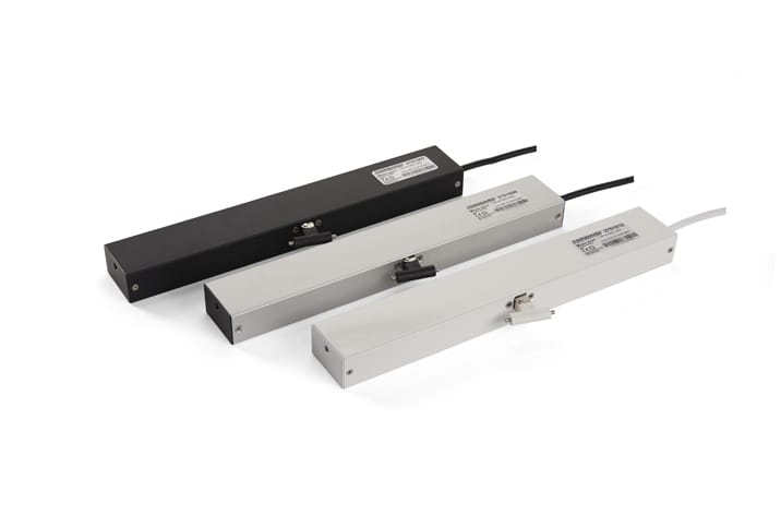 Mingardi Micro Evo1 Window Actuators. Three rectangular industrial devices with labels, arranged in a row on a white background. The devices are in black, light gray, and off-white colors, each having a cable on one end. Perfect for applications like door automation or window actuators.