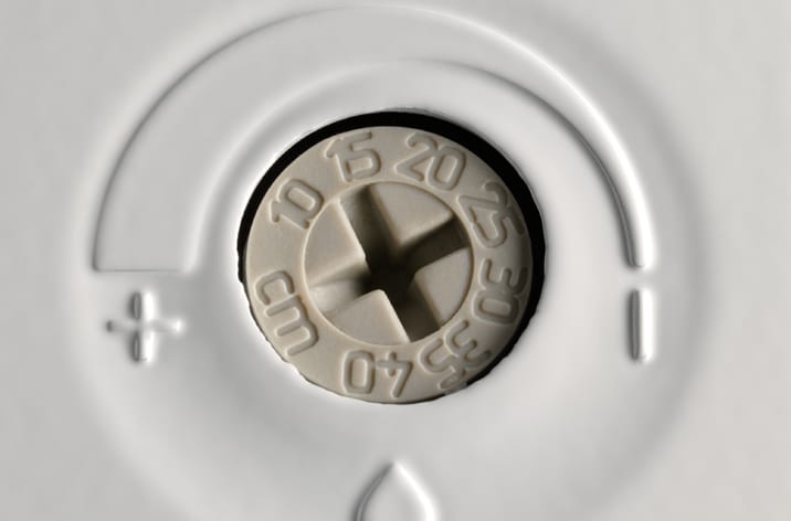Close-up of a white dial with markings from 0 to 40 and plus/minus signs on a white surface, likely part of a door automation or adjustment device.