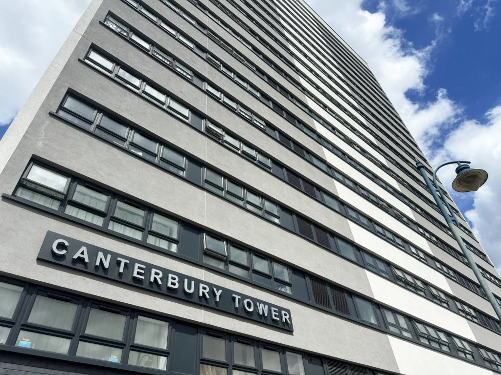 A tall, modern building labelled "Canterbury Tower" photographed from below against a partly cloudy sky.